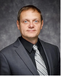 Andrey Ivanov headshot wearing gray suit and tie against gray background