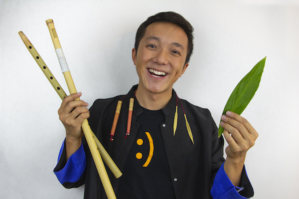 Neng Now smiling holding flutes and a leaf