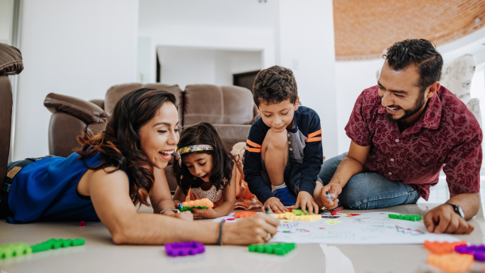 Latino family making a large drawing together, laughing and smiling.