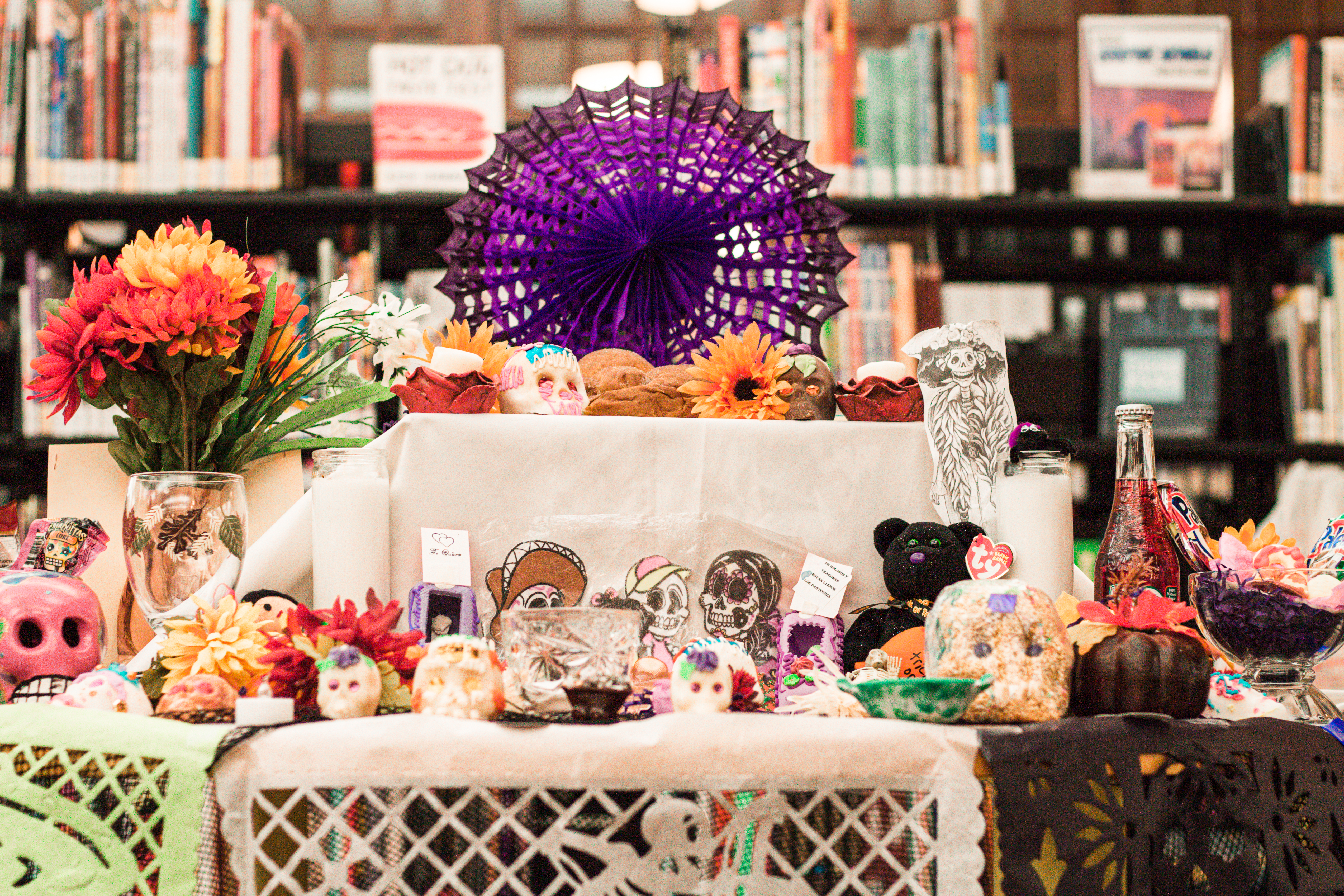 Day of the Dead community altar with brightly colored paper, flowers, sugar skulls and candles.