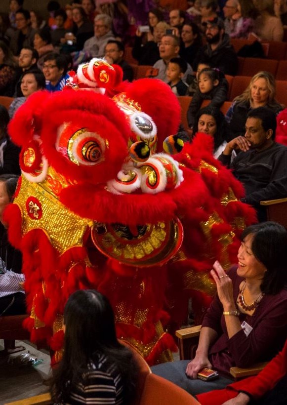 Chinese lion dancers in bright red and yellow traditional costume with crowd in background