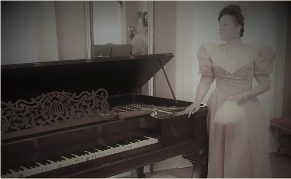 Laura F Keys as Irene Adler, wearing a pink period dress standing by a piano in a photo stylized to look older.