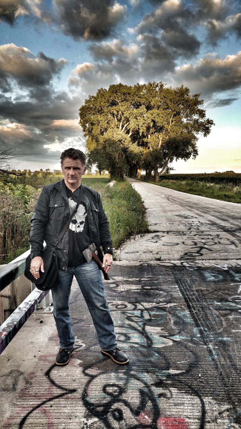 Chad Lewis stands in front of a tree and dark clouds