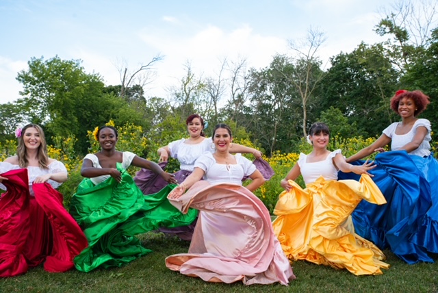Baila Salsa! 6 diverse women wearing dresses with white bodices and different colored flowing skirts (red, green, pink, yellow, blue) swirling their skirts and smiling outdoors