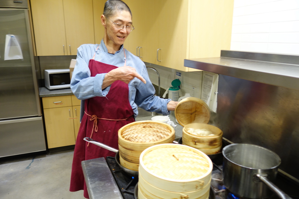 Image of Chef Paul Tseng pointing at dumplings as they steam