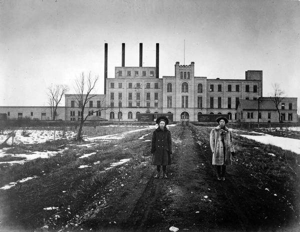 black and white image of 2 women standing in front of the Garver feed mill circa 1924